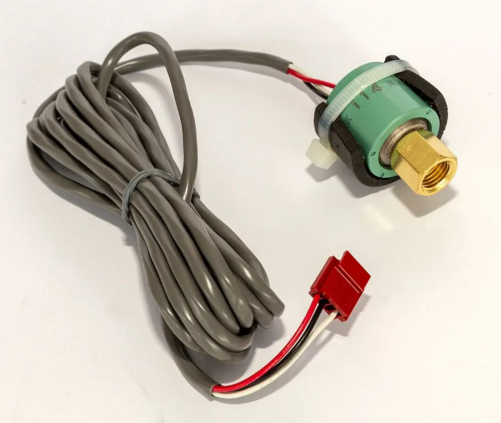 Drucksensor von Daikin mit grünem Gehäuse und goldener Anschlussschraube, umgeben von grauen Kabeln mit einem roten Stecker und zwei weiteren Leitungen.